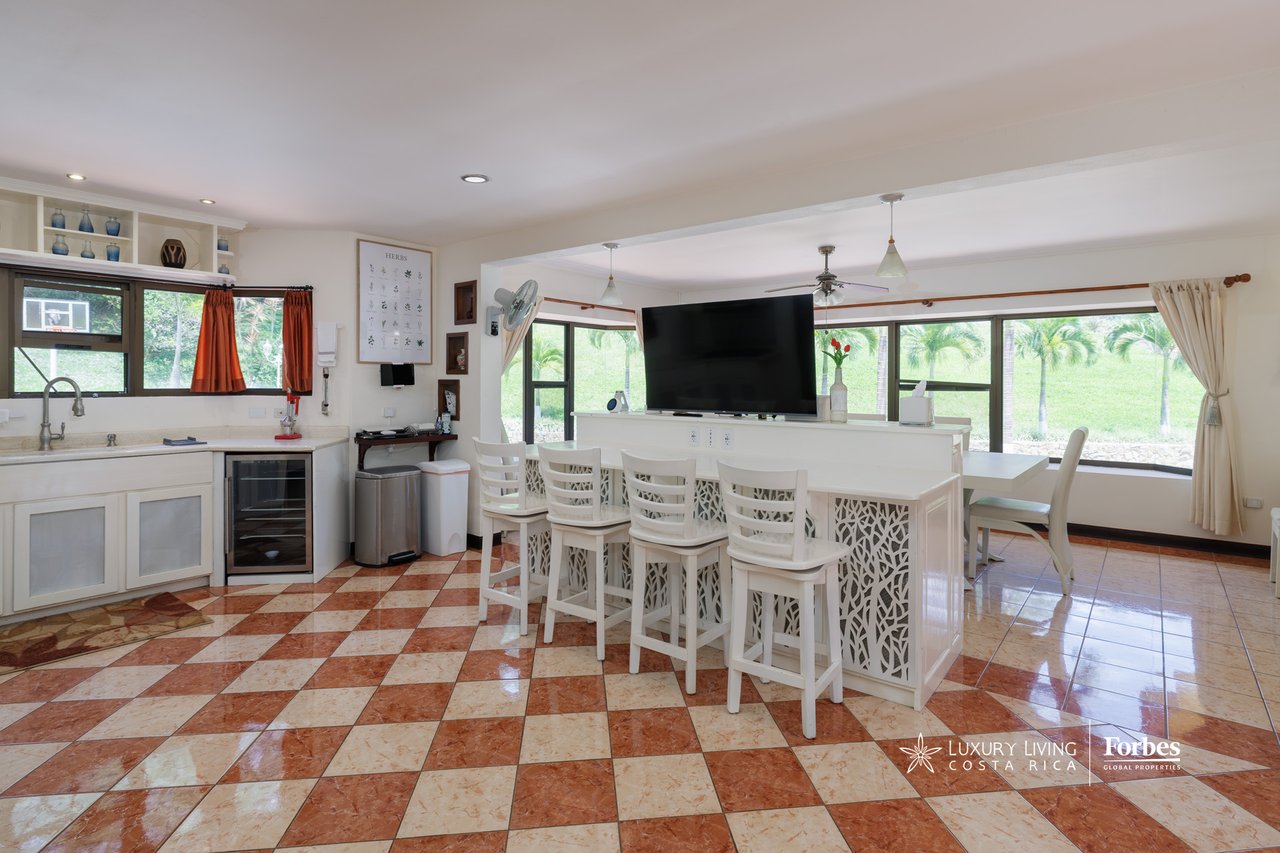 Open-plan kitchen and dining area with a white island, bar stools, and checkerboard tile floor.