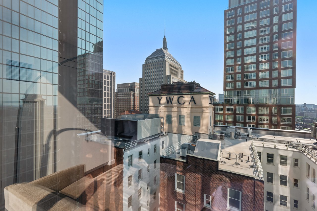 City skyline viewed through a high-rise window, with the YWCA building in the foreground.