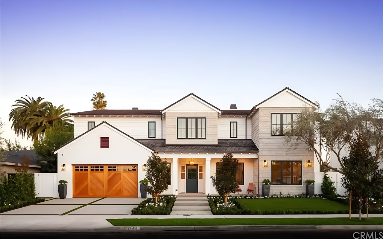A two-story modern farmhouse-style house with a light-colored exterior and a wooden garage door.