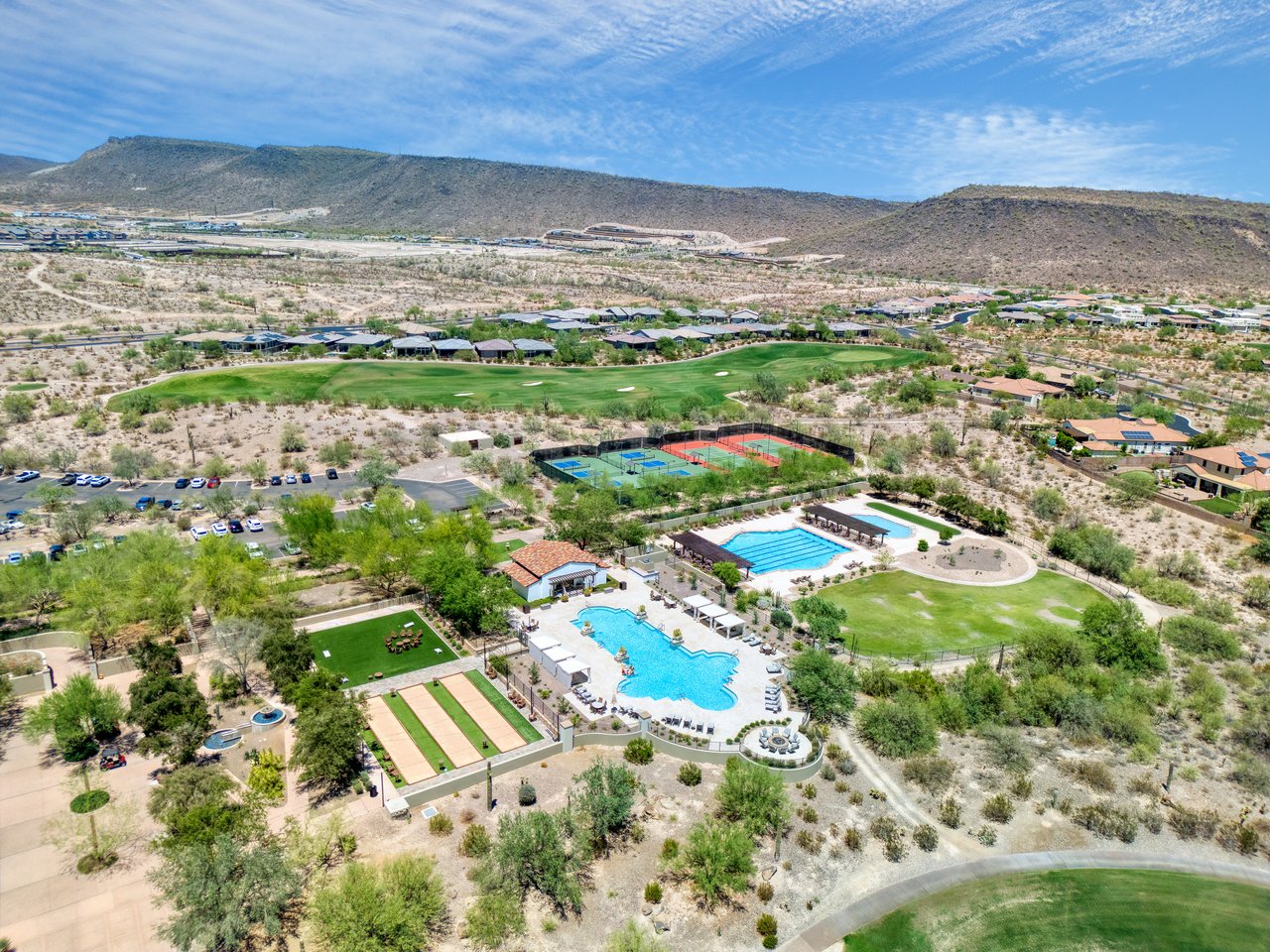 Aerial view of the community amenities near 30959 North 120th Ave, including swimming pools, tennis courts, sports fields, and desert landscaping with mountains in the distance.