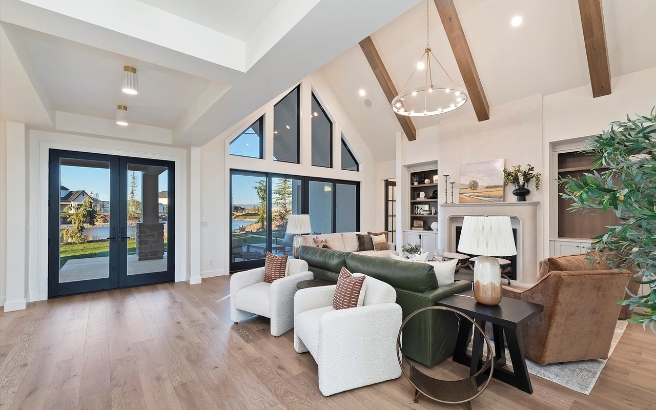 Living room with vaulted ceiling, wood beams and floor-to-ceiling windows overlooking the lake