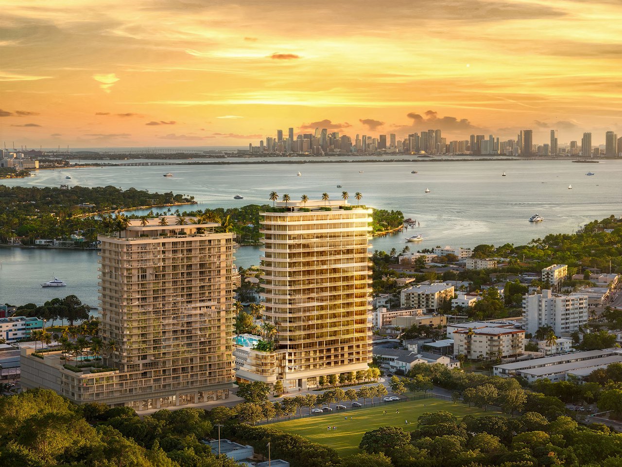 72 Carlyle waterfront residences with twin towers, Biscayne Bay, and the Miami skyline at sunset.