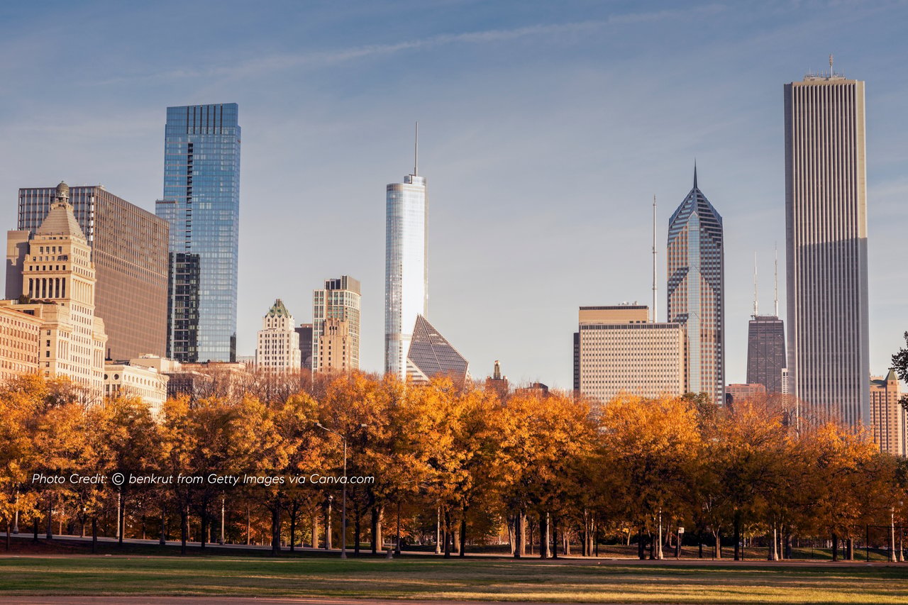 Chicago skyline rising behind a park with golden autumn trees.