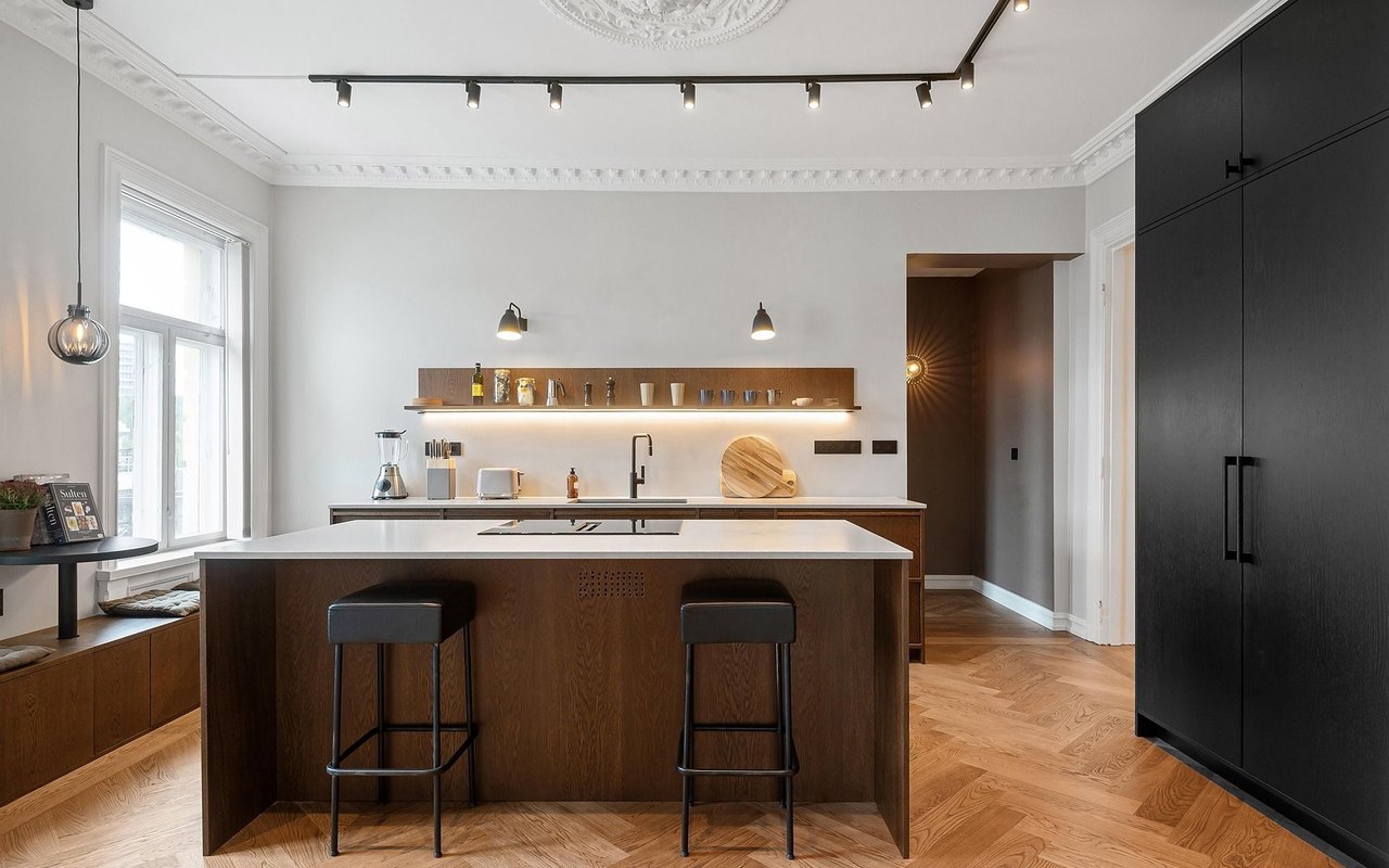 Modern kitchen with a dark wood island, black cabinetry, and parquet flooring.