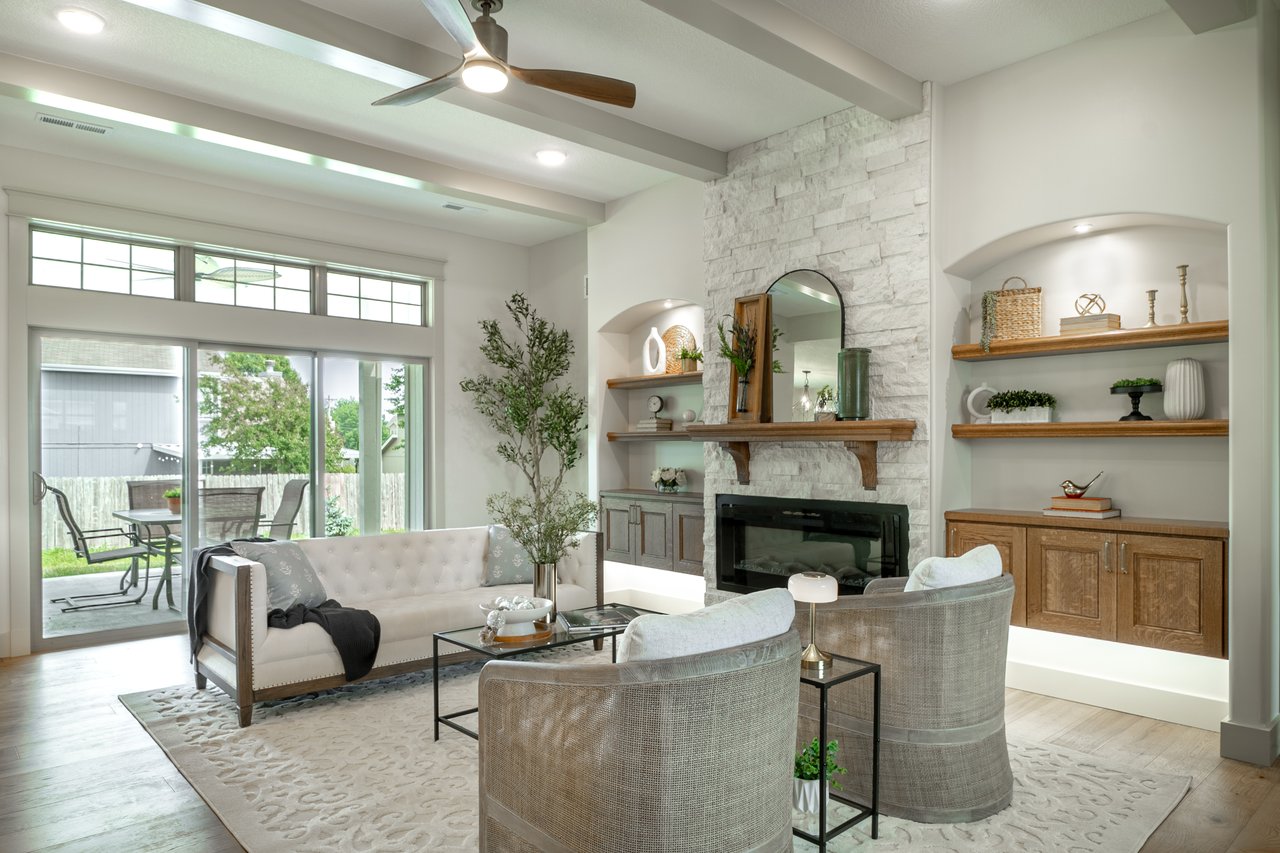 Staged living room with a white stone fireplace, built-in shelves, and sliding doors to a patio.
