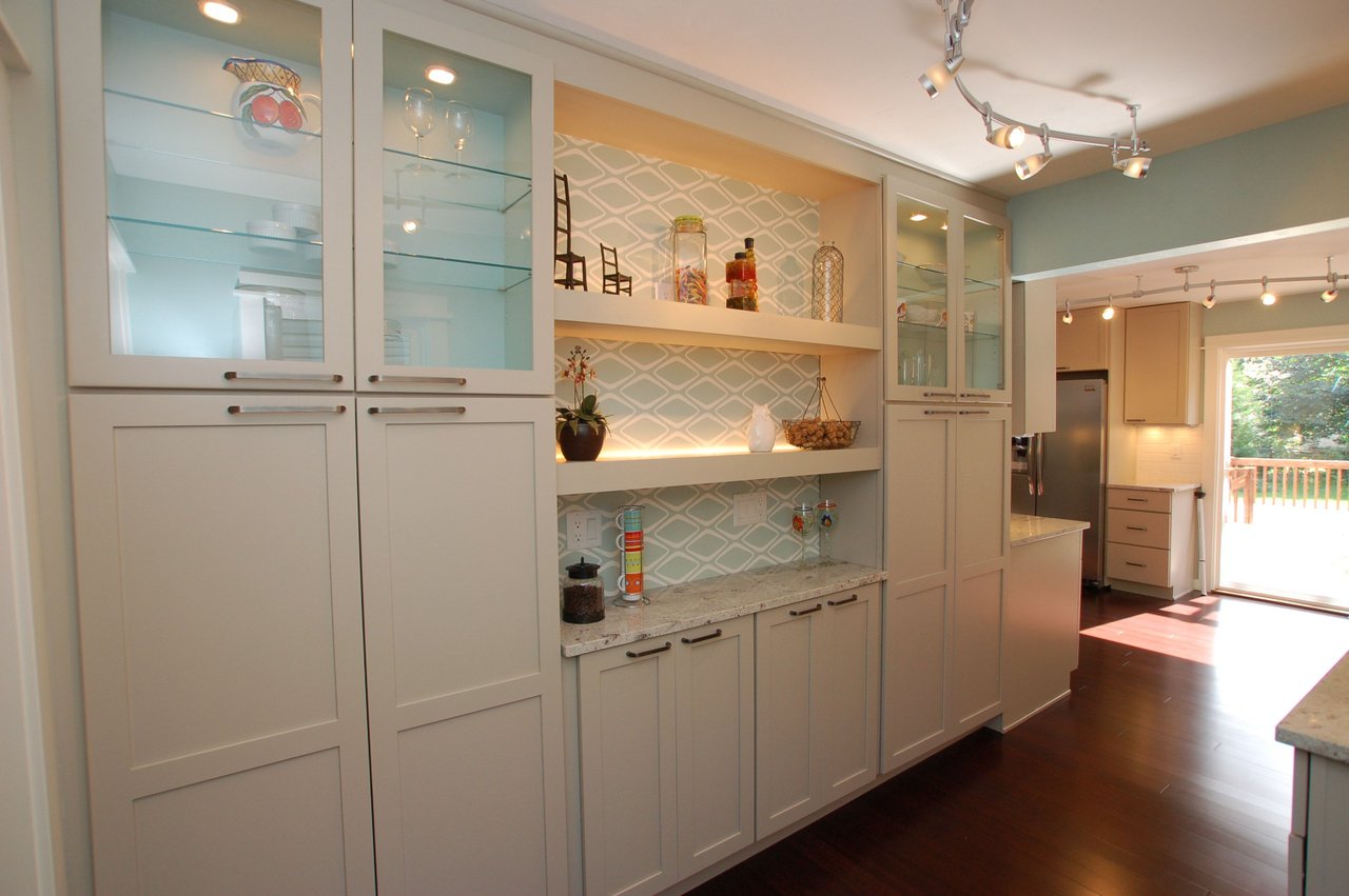 Kitchen with white cabinetry, patterned backsplash, and glass-front cabinets beside a deck door.