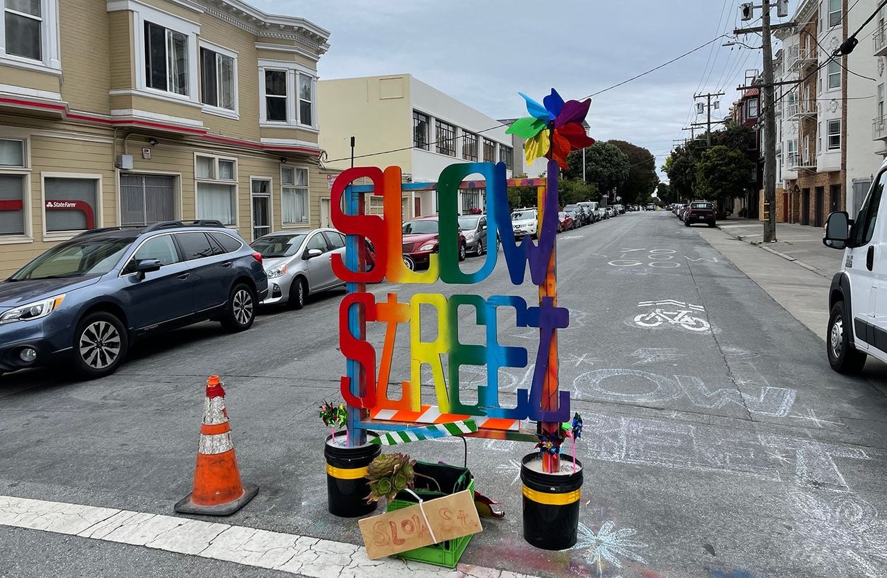 Colorful Slow Street sign on residential San Francisco street with parked cars