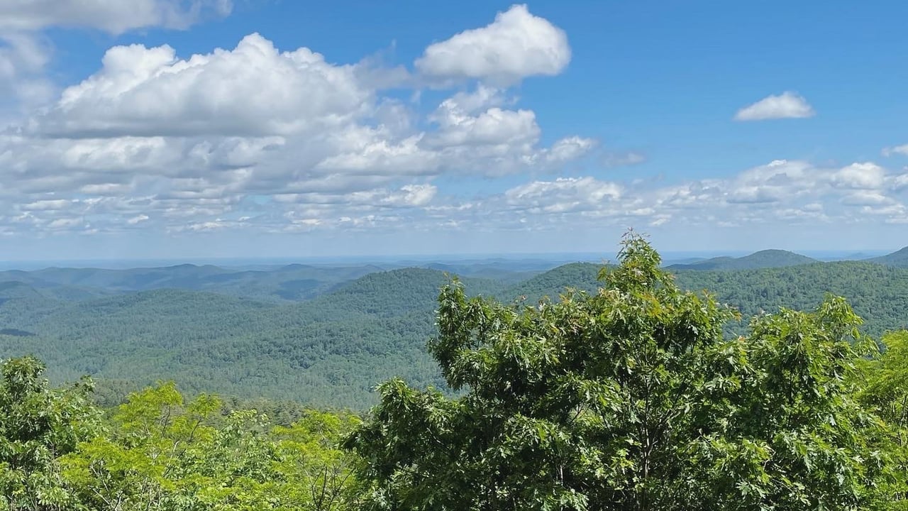 Long-range view of forested Blue Ridge Mountains under a blue sky near Highlands, NC