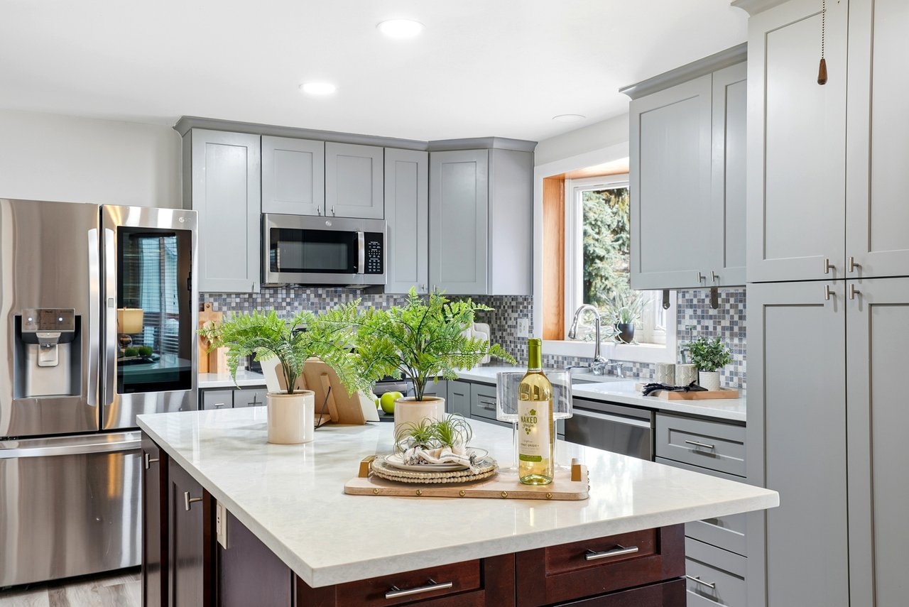Updated Colorado kitchen with gray cabinets, quartz countertops, stainless steel appliances, and a large island showcasing home improvements that increase resale value.