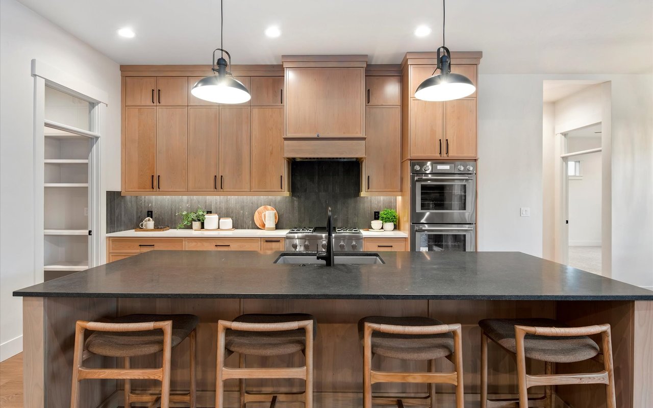 Modern kitchen with large island, oak cabinets, and thin vertical slate-colored tile backsplash