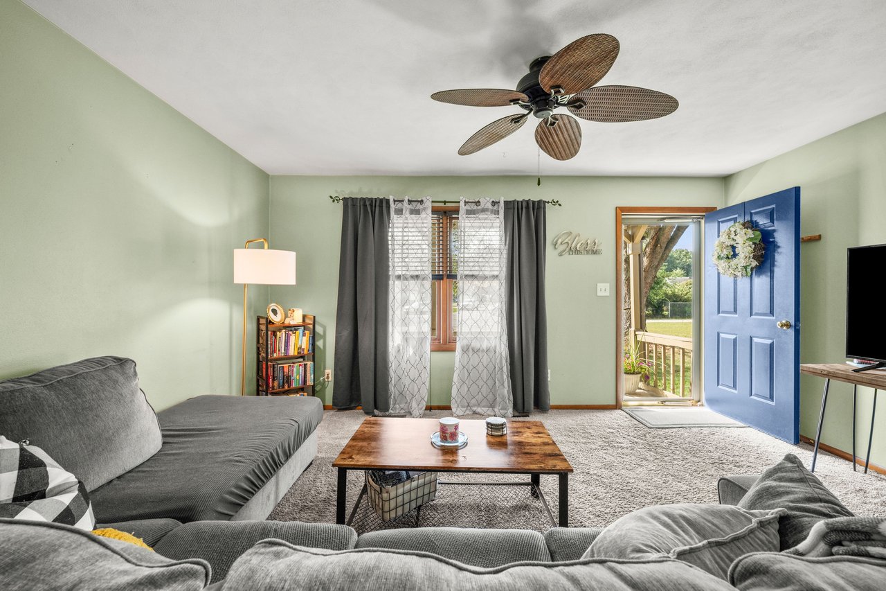 Living room with gray sofas, a wooden coffee table, and an open blue front door.