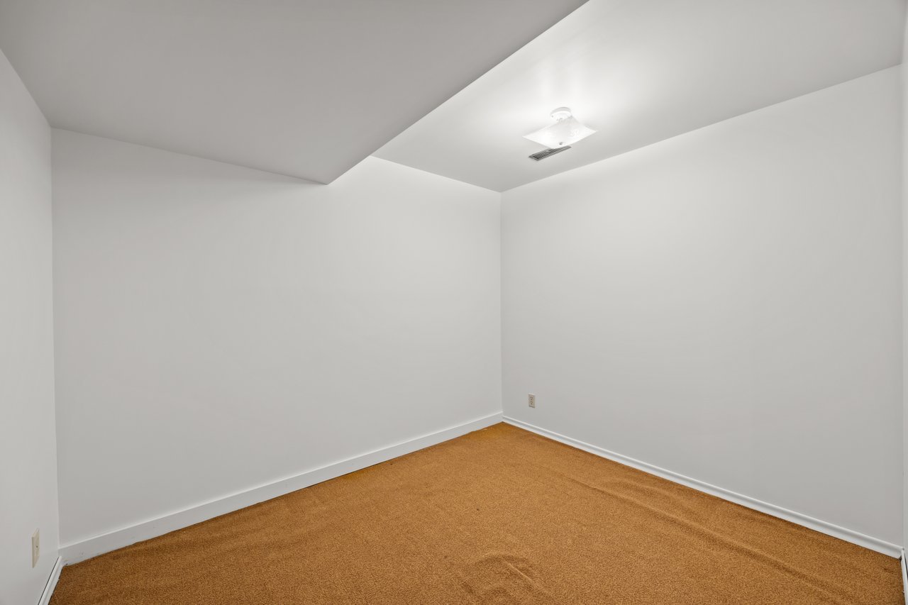 Empty room with tan carpet and a stepped ceiling with a light.