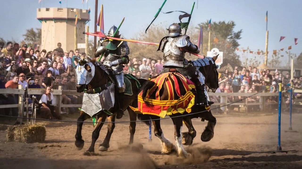 Armored riders joust on horseback before a crowd at the Minnesota Renaissance Festival.