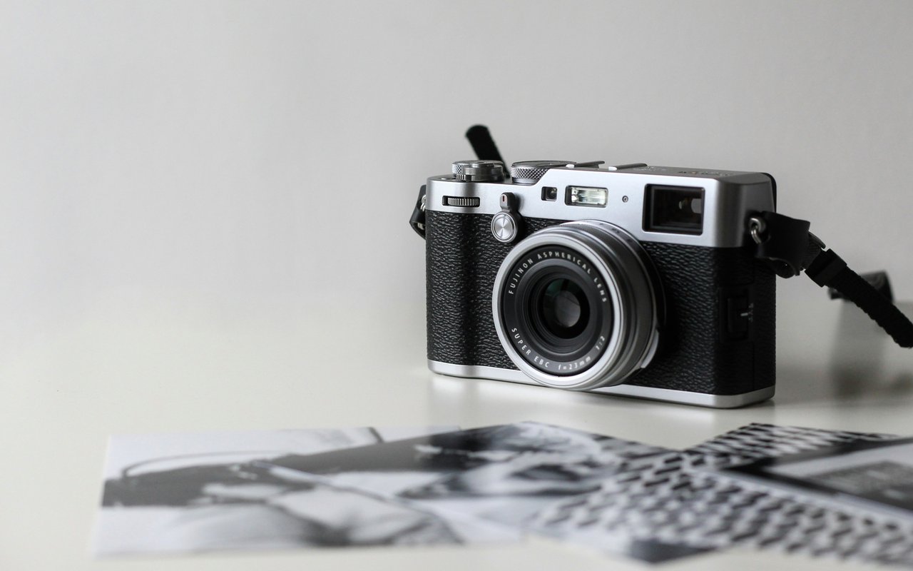 Silver-and-black compact camera beside blurred black-and-white photographs.