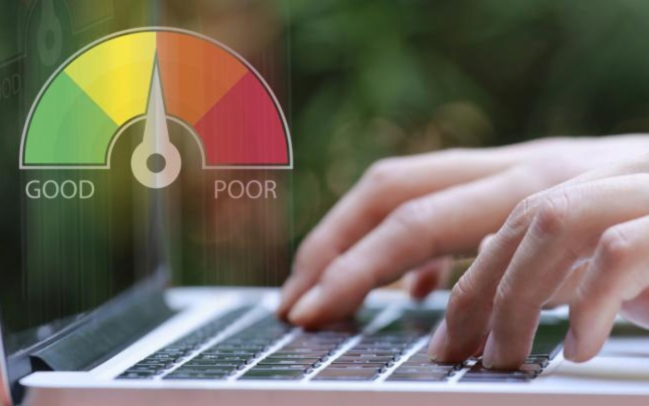 Hands type on a laptop beside a colored credit gauge labeled GOOD and POOR.