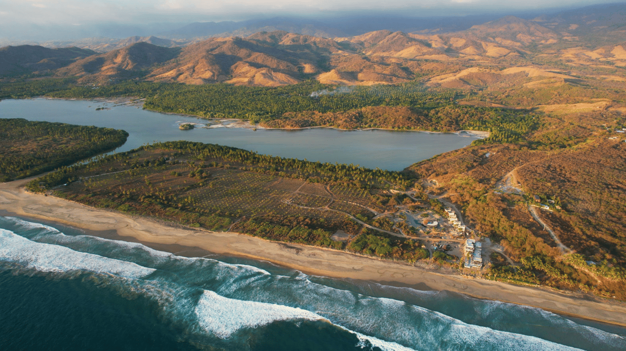 Aerial view of MUSA Mexico coastline with beachfront, river lagoon, and surrounding mountains