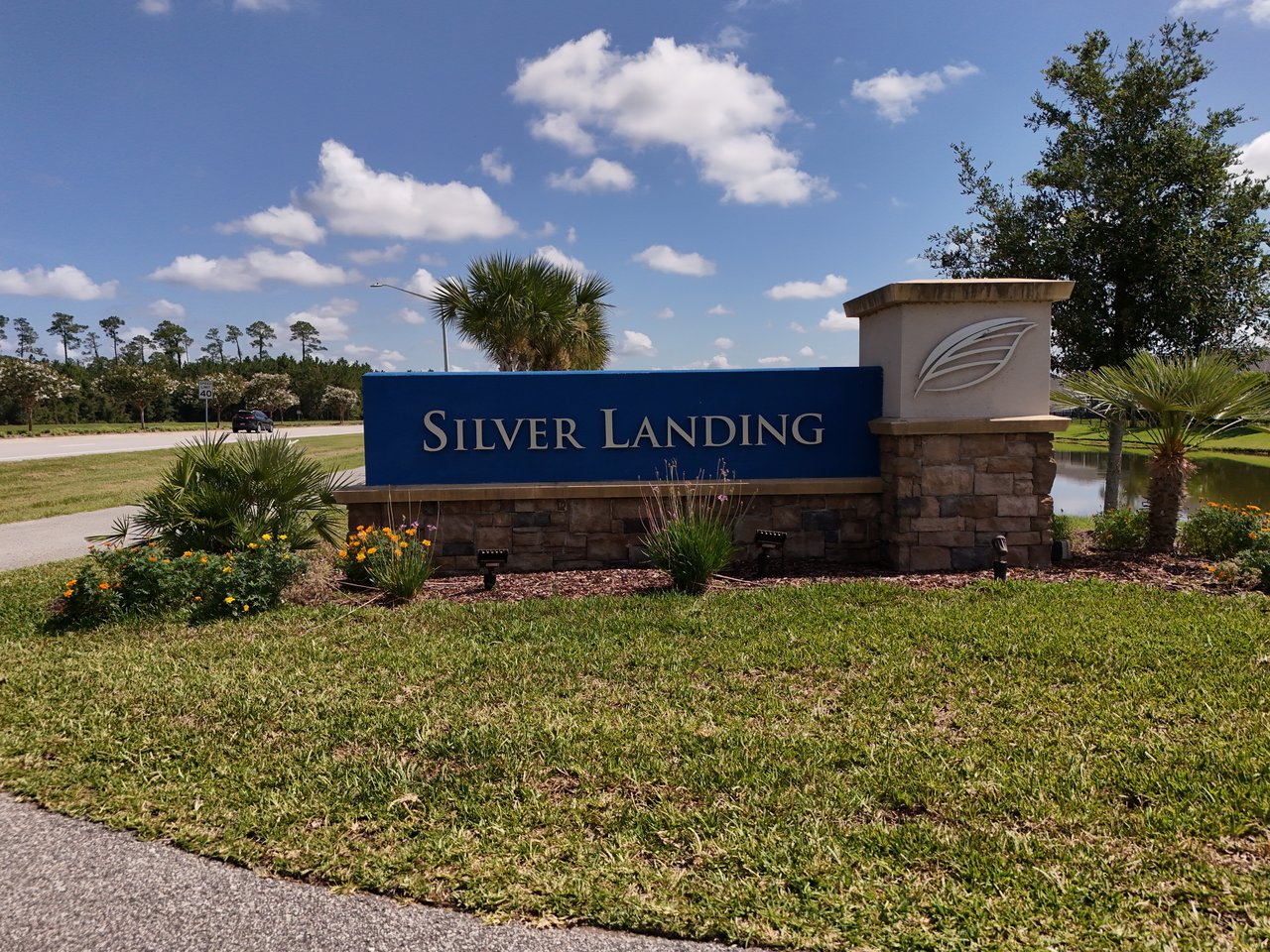 Silver Landing entrance sign with stone base, landscaped lawn, and pond.