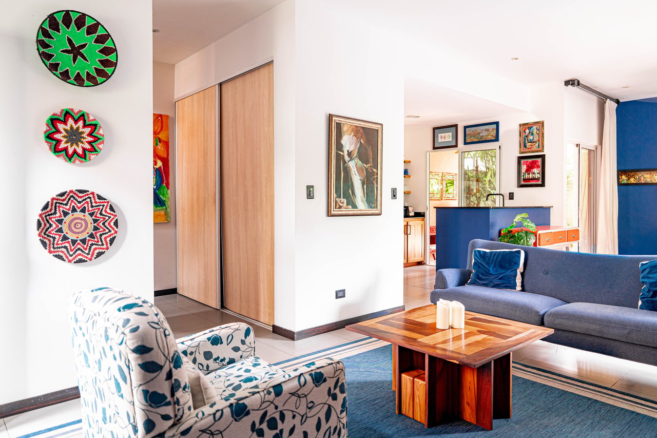 Living room with a blue sofa, patterned armchair, and colorful woven wall decorations.