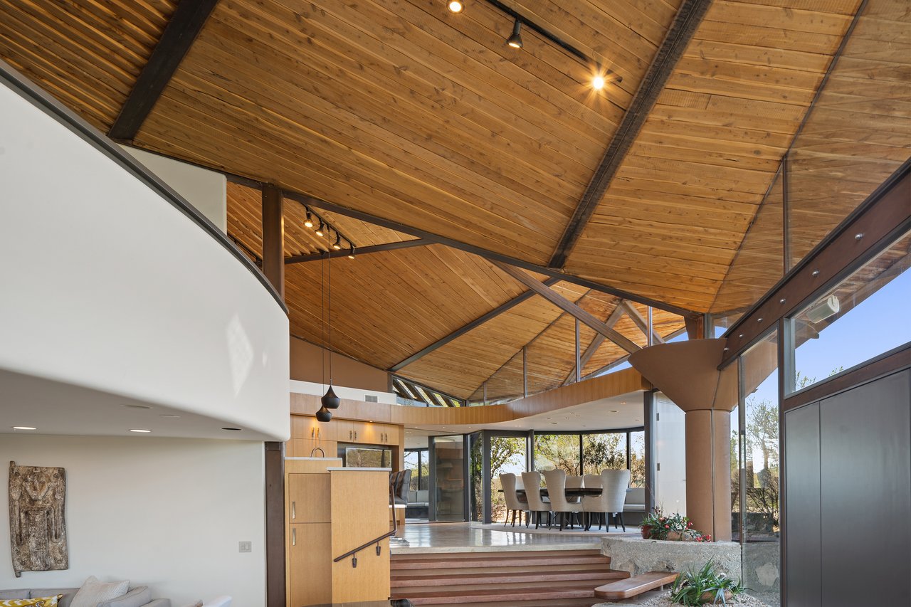 Great room beneath a vaulted wood ceiling carried on exposed steel trusses, designed by architect John Covert Watson, 4002 Tyx Trail, Spicewood, Texas.