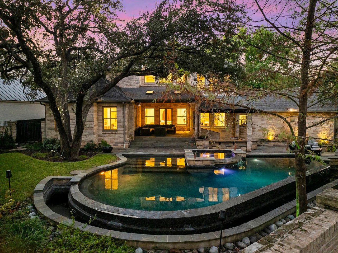 Twilight view of the rear exterior, pool, and spa at 5902 Saratoga Cove, Davenport Ranch, Austin, Texas, built by John Luce.