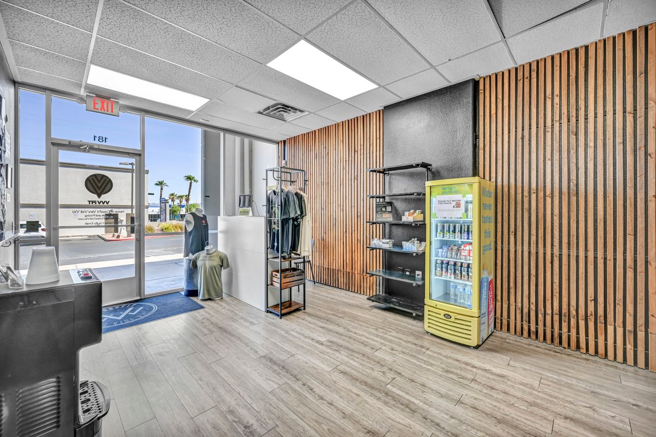 Retail shop interior with clothing displays, a beverage cooler, and wood-slat walls.