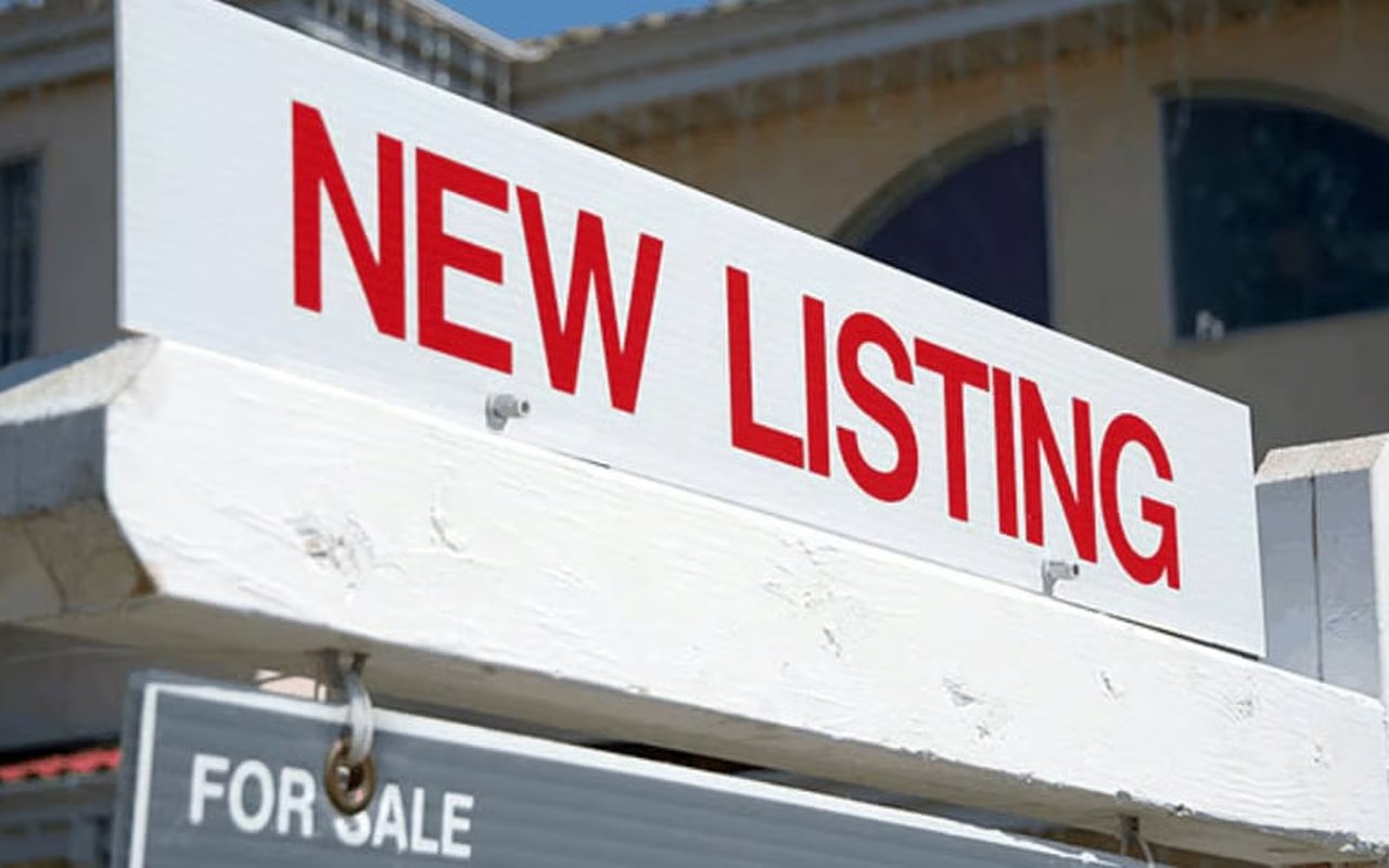 New listing sign above a for sale sign outside a house.