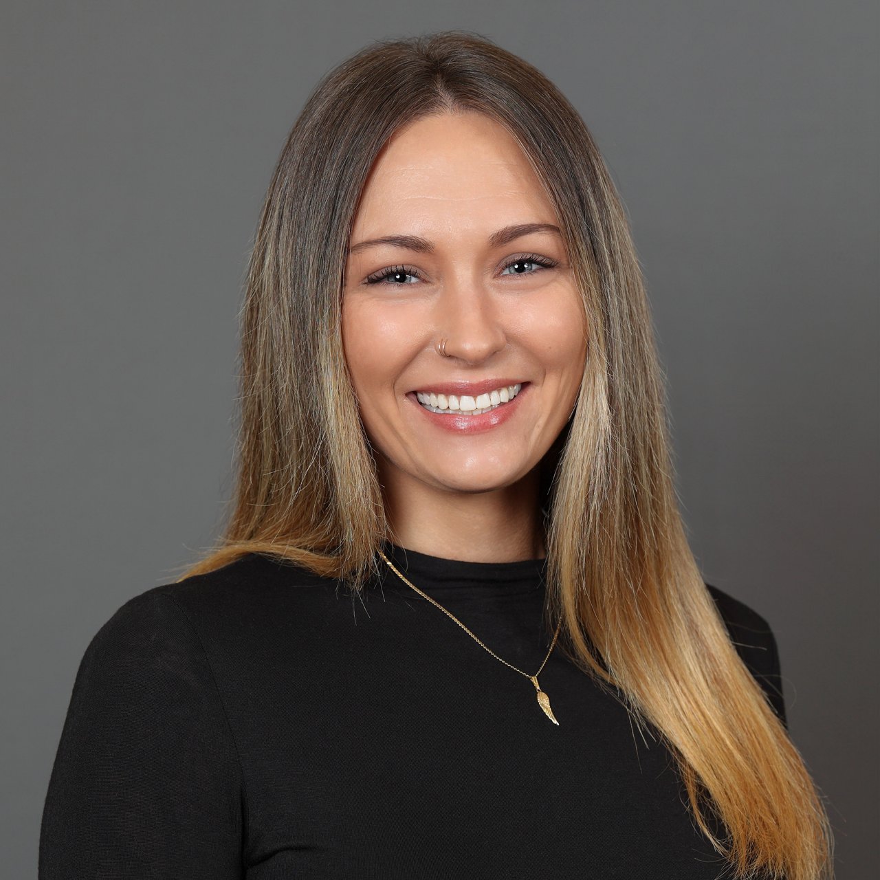 Erica Poniatowski smiling in a black top and gold pendant necklace.