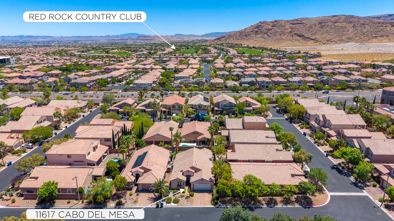 Aerial view of 11617 Cabo Del Mesa, showing surrounding homes and distant desert mountains.