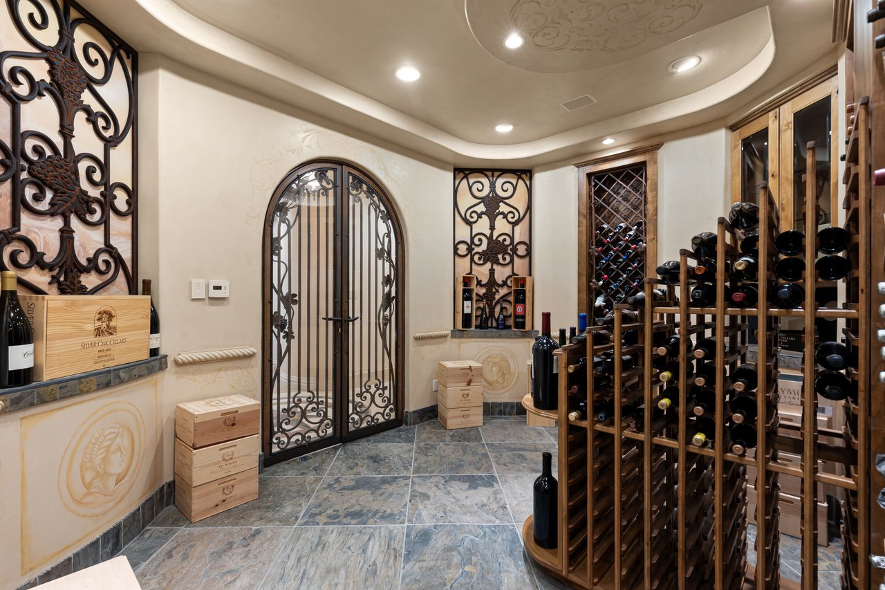 Wine cellar with wooden wine racks and an ornate wrought-iron arched gate.