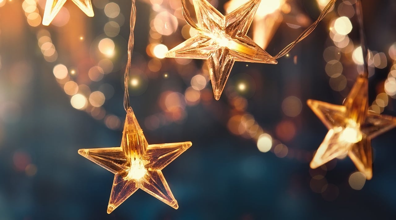 Glowing golden star-shaped holiday lights against a dark, softly blurred background.