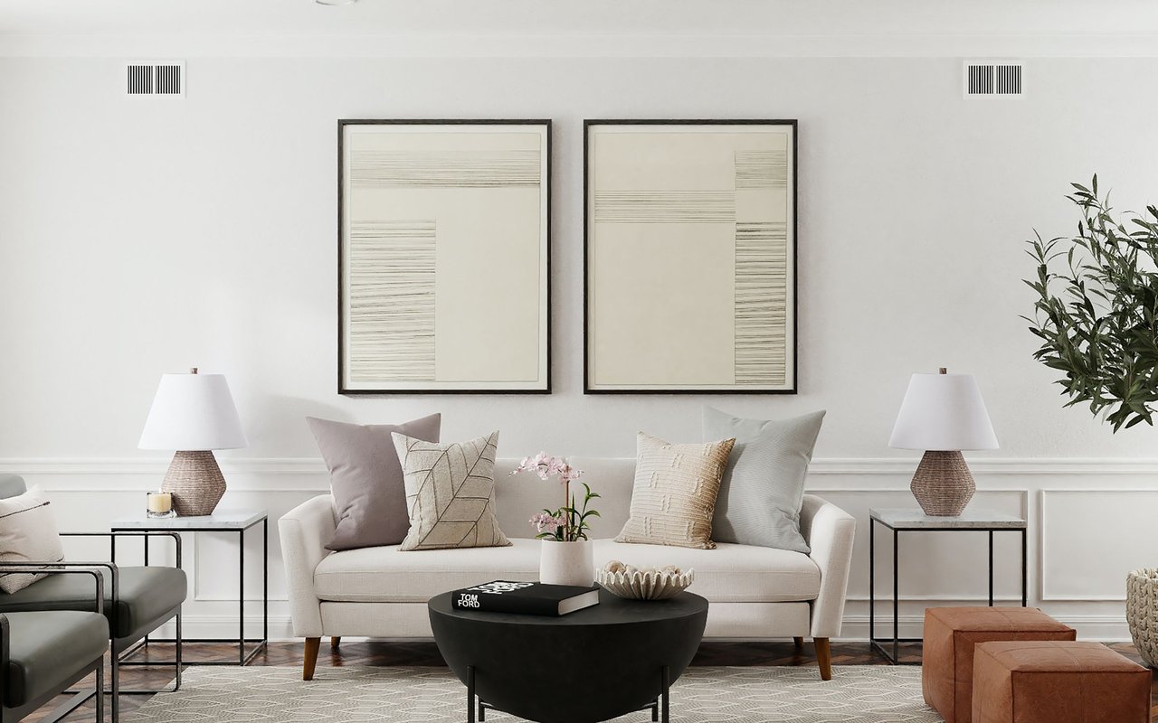 Staged living room with a cream sofa, black coffee table, and paired framed abstract prints.