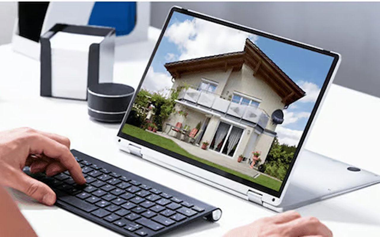 Person browsing a two-story house on a laptop during an online property search.