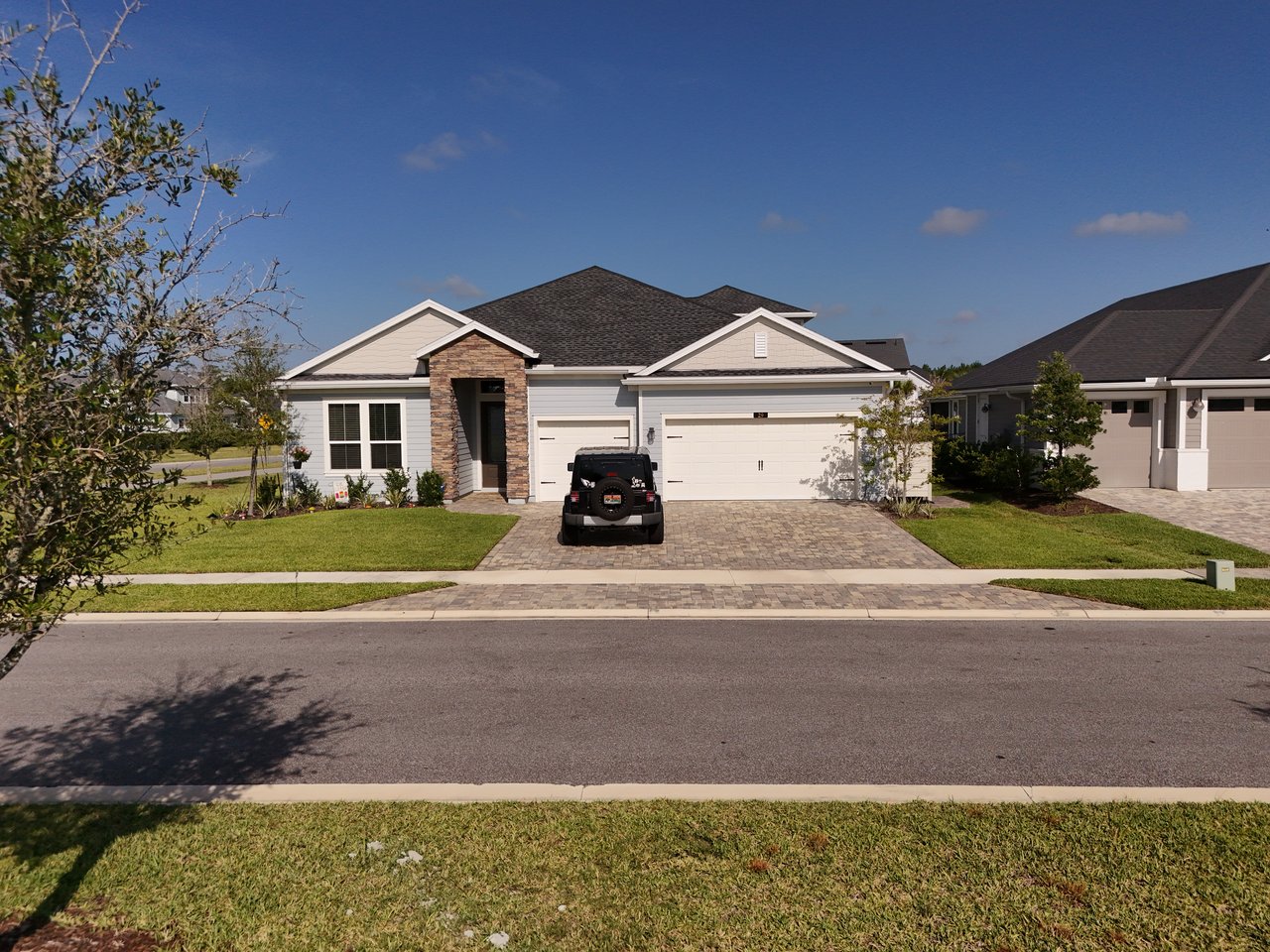 Single-story home with a stone-accented entry, attached garage, and a black Jeep in the driveway.