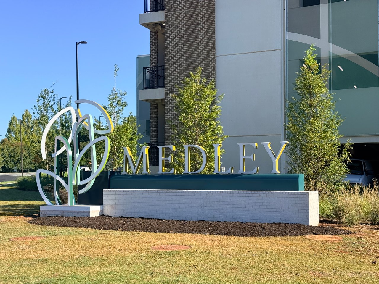 Medley development sign in front of a modern glass-and-brick building.