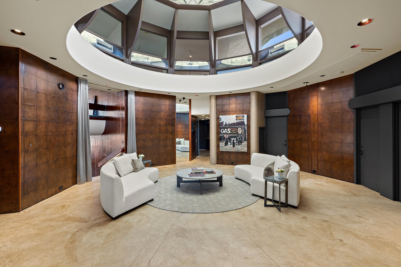 Rotunda lounge beneath a faceted domed skylight, with curved paneled walls and stone flooring, designed by architect John Covert Watson, Spicewood, Texas.
