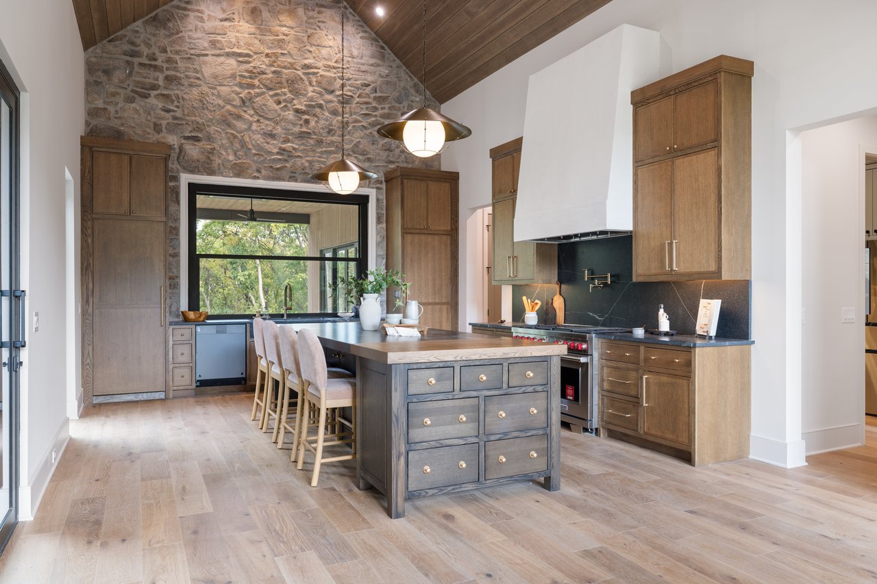 Kitchen with a large island, vaulted wood ceiling, and dramatic stone wall.