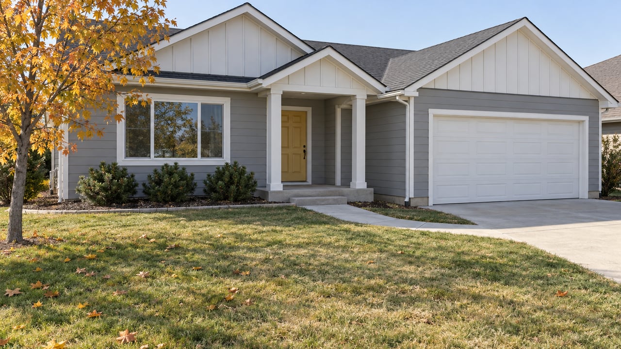 Gray single-story home with white-trimmed gables, a mustard entry door, attached garage and autumn lawn.
