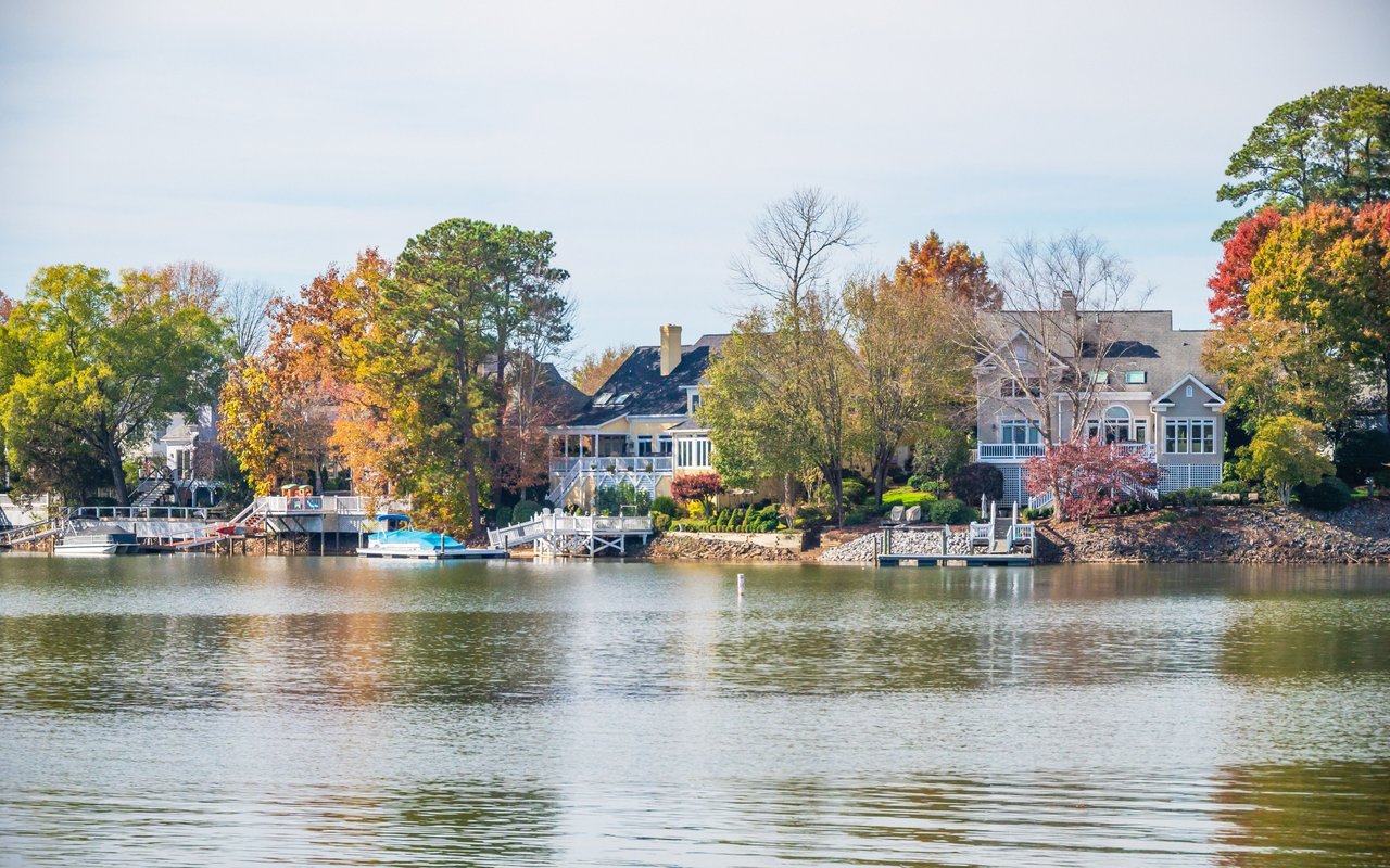 Waterfront homes with private docks and autumn trees along a lake.