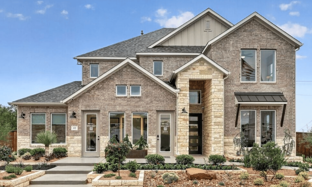 Two-story brick and stone home with a covered entry and landscaped front yard.