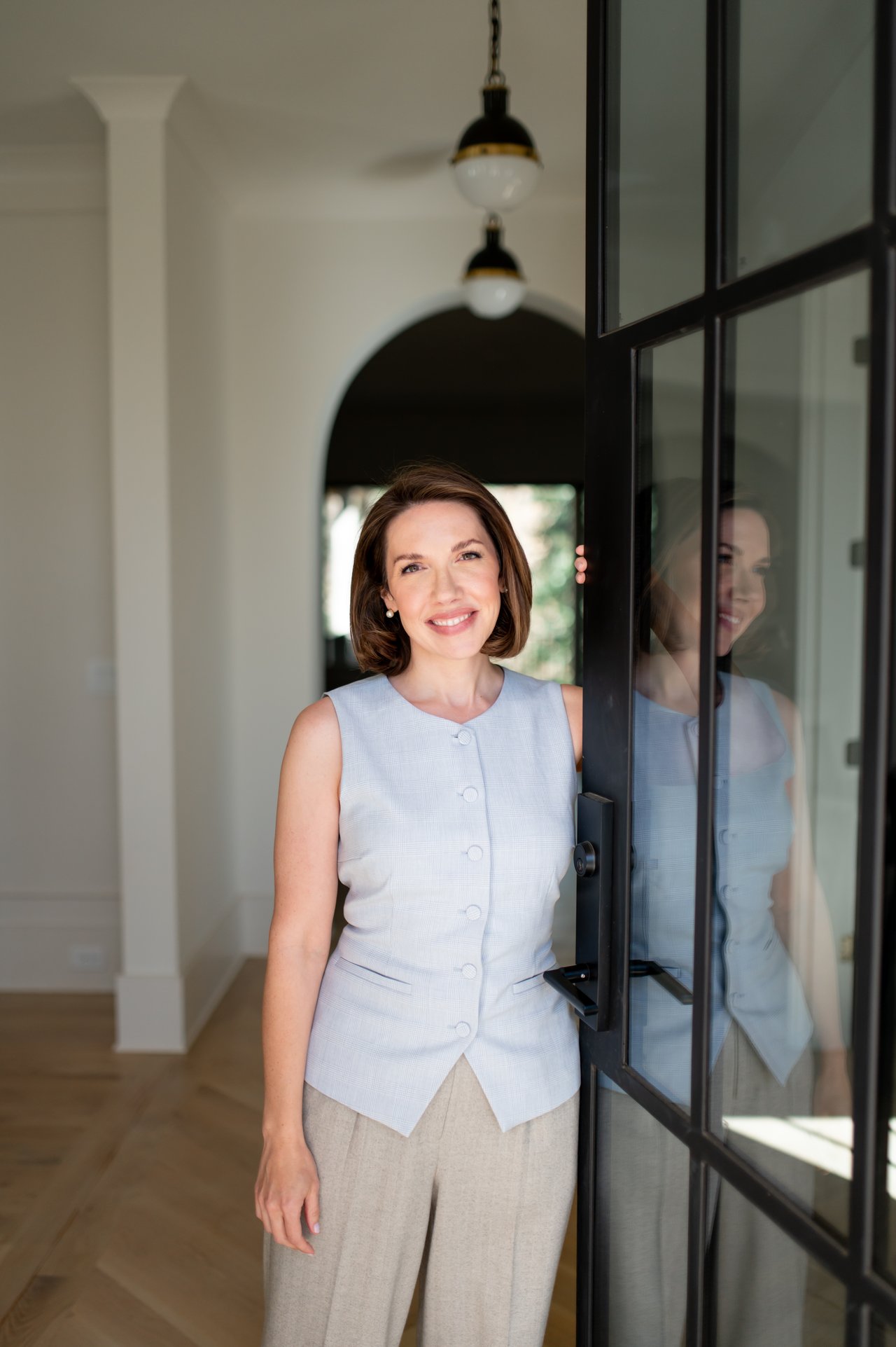 Lauren Bowling smiles beside a black-framed glass door inside a home.