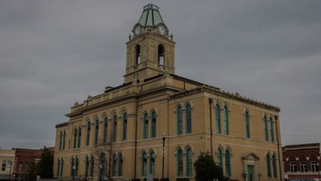 Historic tan civic building with arched windows and a prominent clock tower.