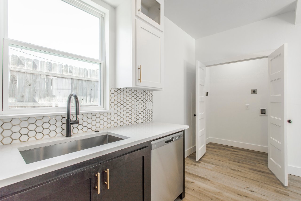 Modern kitchen with honeycomb tile backsplash, stainless steel sink, and dark cabinetry.