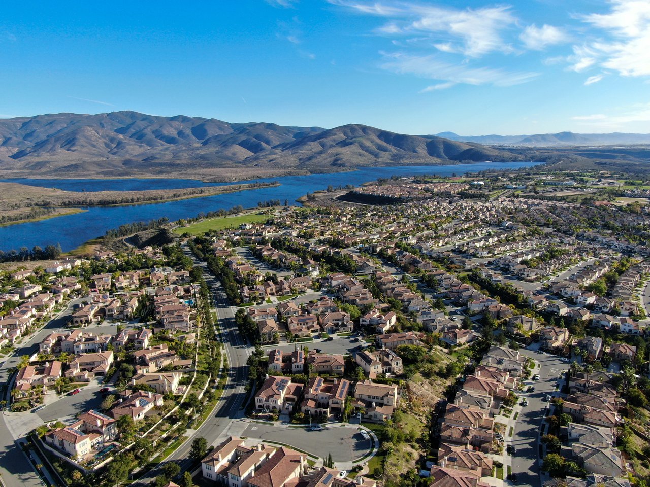 Aerial view of Chula Vista homes beside a reservoir, with mountains in the distance.