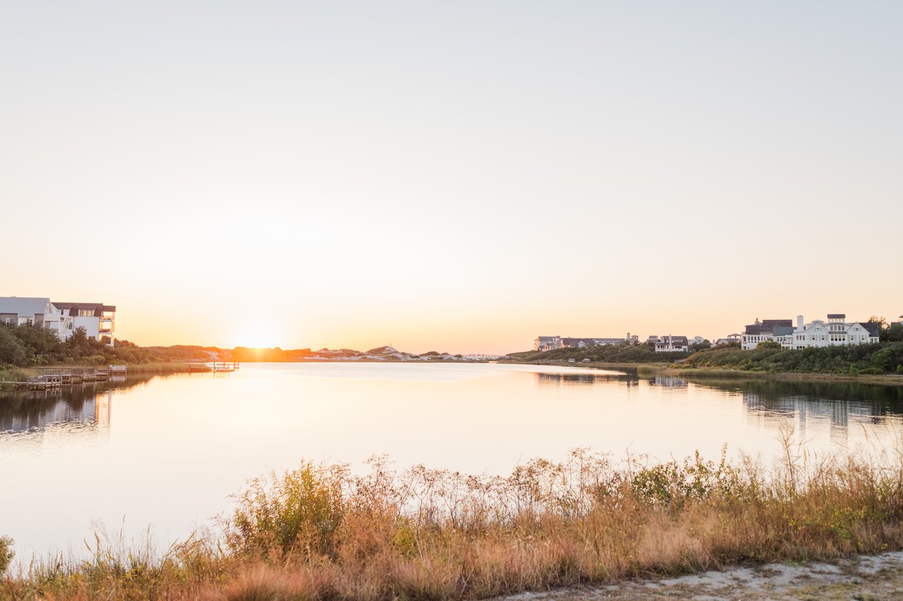 Wide sunset over a 30A coastal dune lake with silhouetted gulf-front homes near Seagrove Beach, Florida