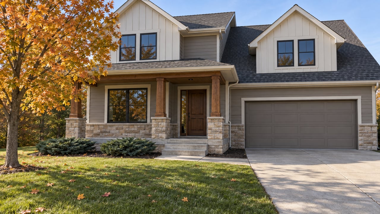 Autumn morning light on a two-story home with mixed siding, a stone-based porch, attached garage and deep front lawn.