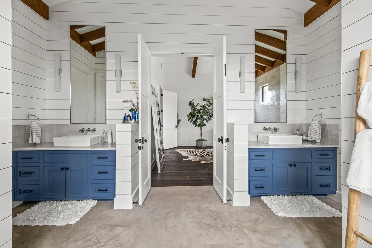 Bathroom with dual vanities, blue cabinetry, and shiplap walls in this Creek Road Ranch home in Dripping Springs, Texas.