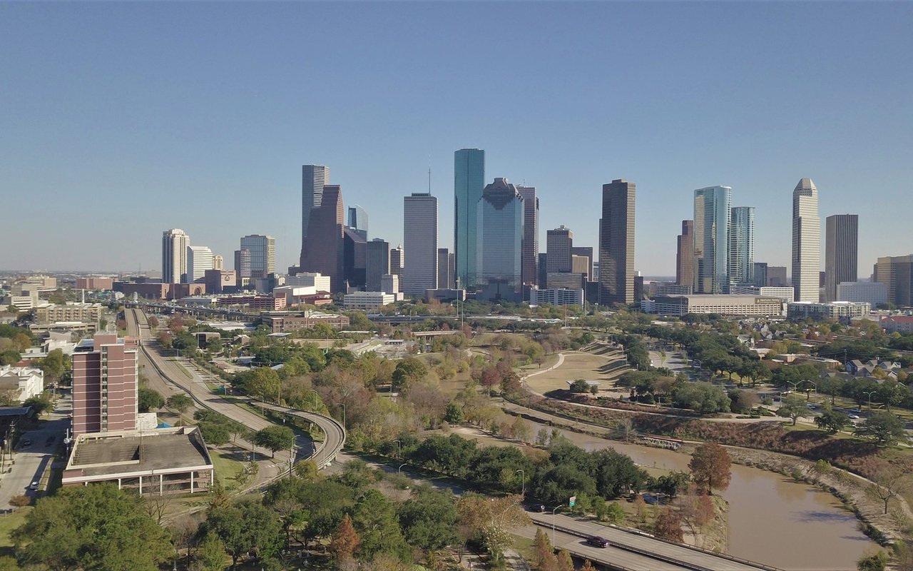 Downtown Houston skyline above a winding bayou and parkland.
