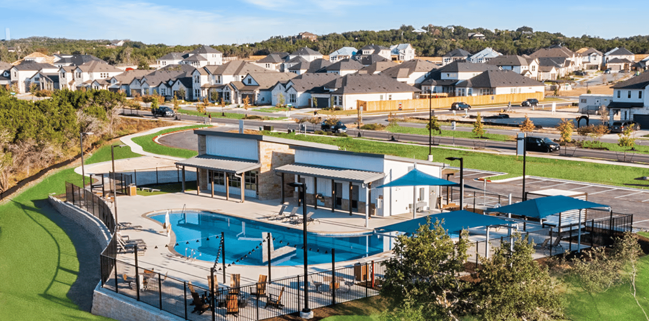 Neighborhood community pool and amenity center with rows of houses behind it.