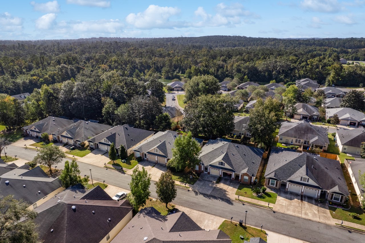 Aerial neighborhood view showing 5441 Hampton Hill Circle, Tallahassee, Florida 32311 and surrounding homes with tree-lined backdrop.