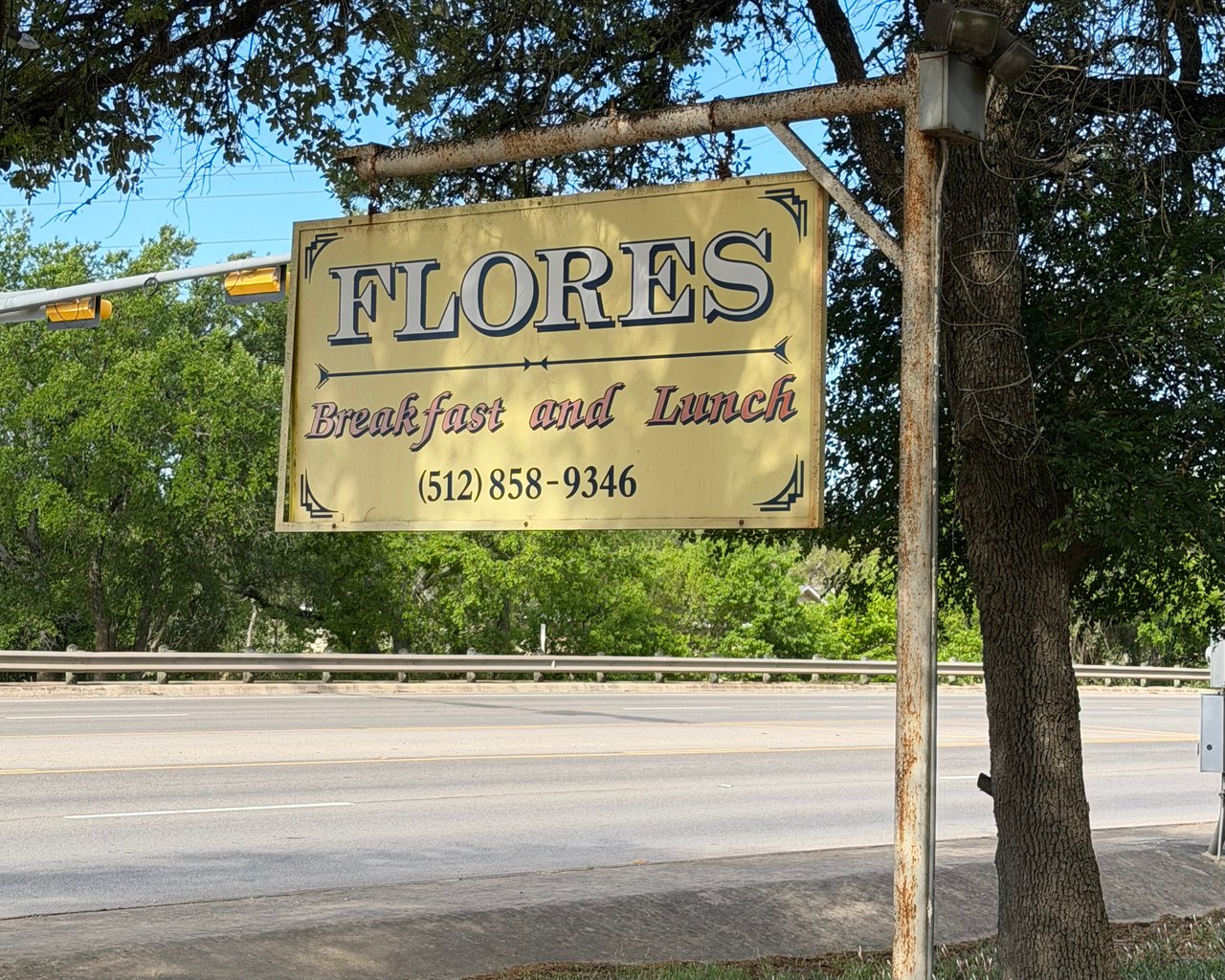 Flores Breakfast and Lunch roadside sign beneath trees